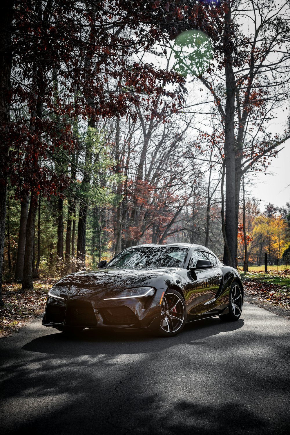 black porsche 911 parked on road near trees during daytime