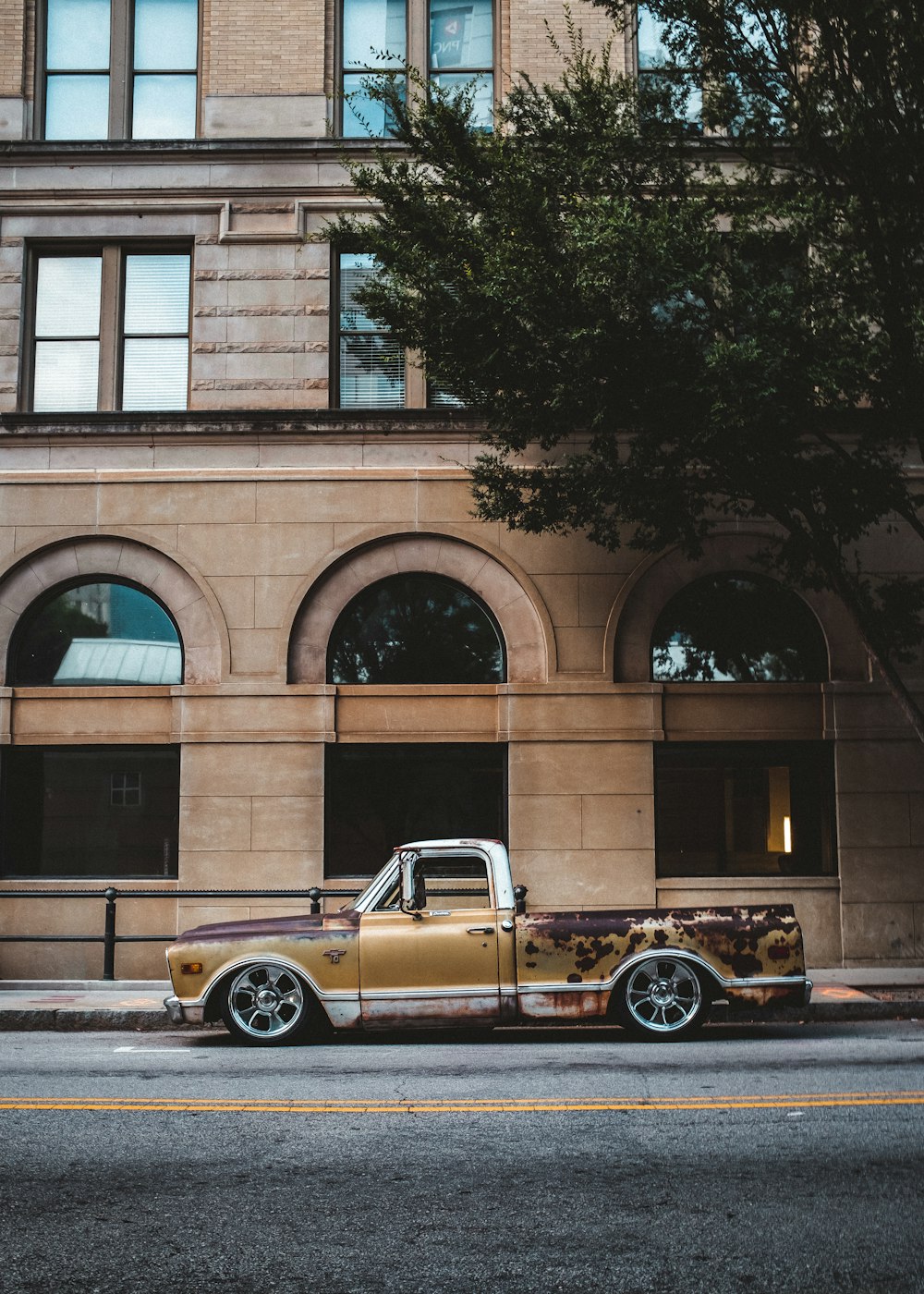 brown coupe parked beside brown concrete building during daytime