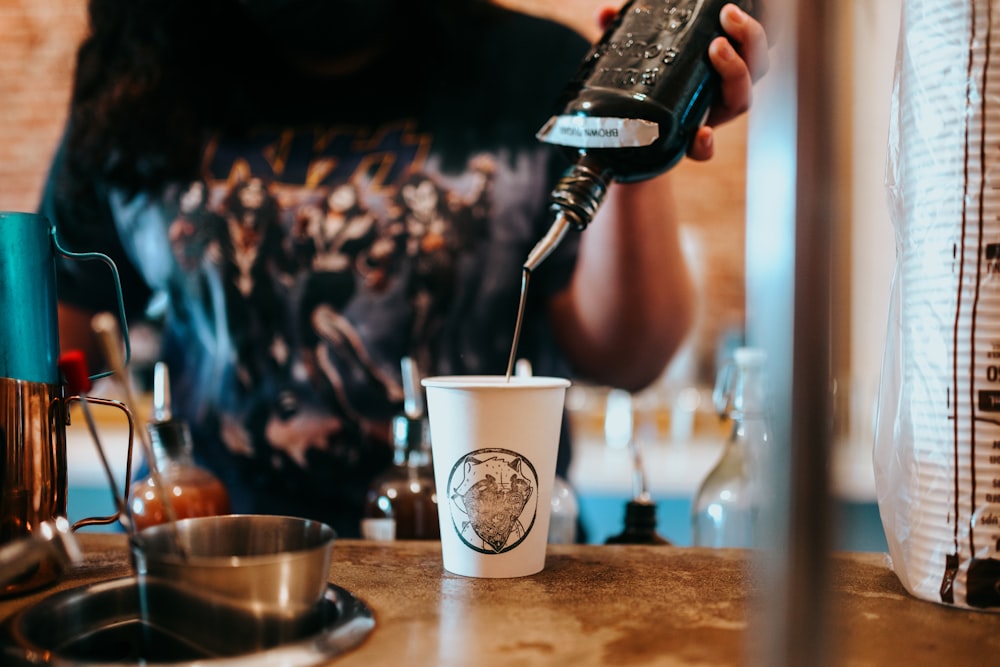 person pouring white starbucks coffee on silver cup