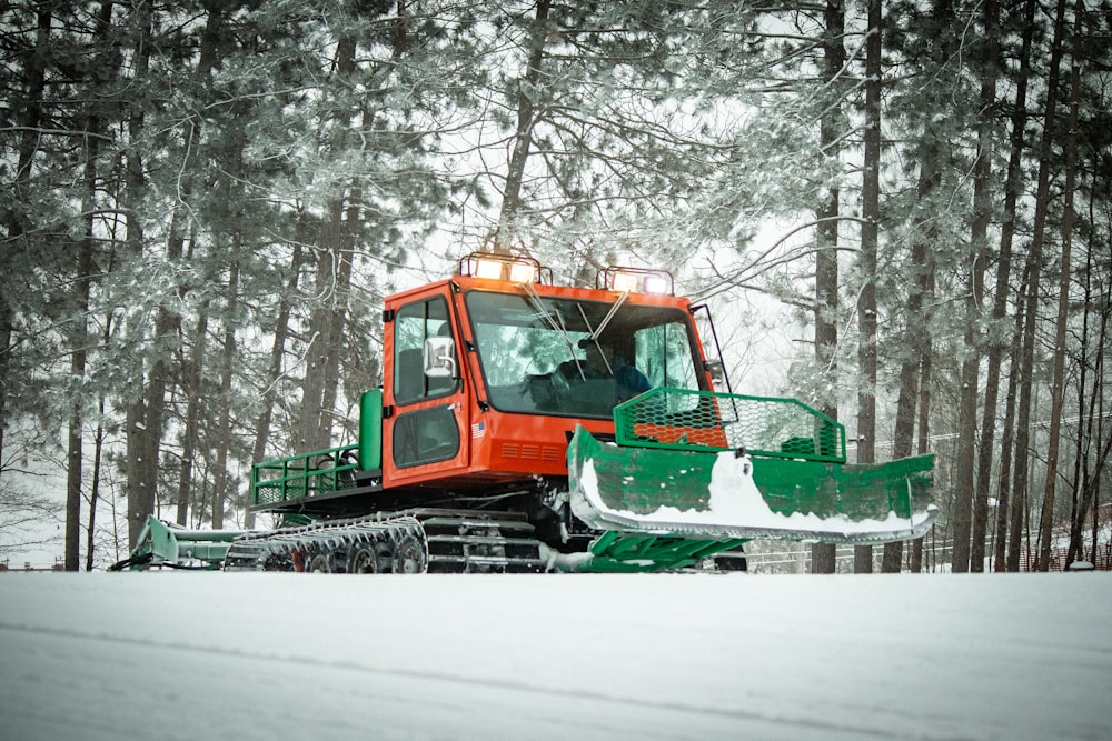 日中の雪に覆われた地面を走る緑と茶色のトラック