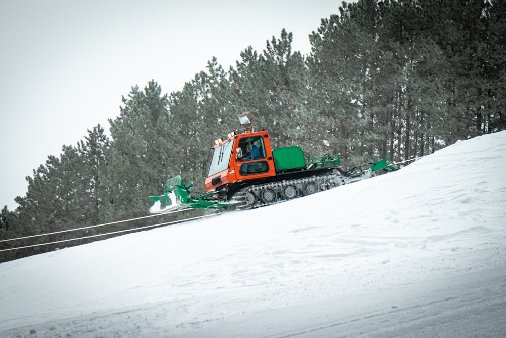 green and orange tractor on snow covered ground during daytime