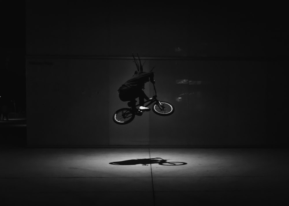 grayscale photo of man riding bicycle