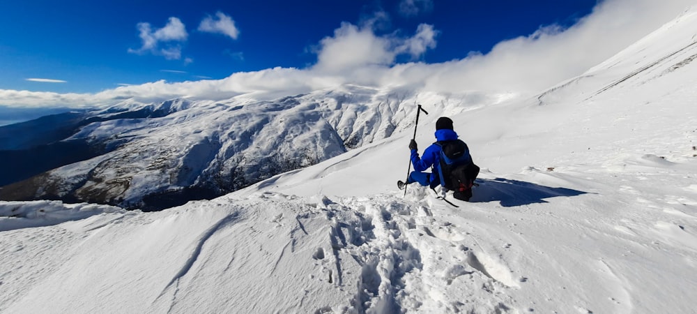 person in blue jacket and black pants on snow covered mountain under blue and white sunny