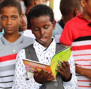 man in red and white polo shirt holding yellow book