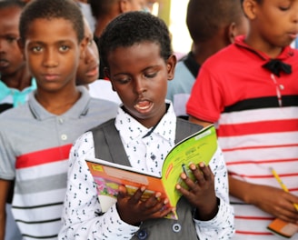 man in red and white polo shirt holding yellow book