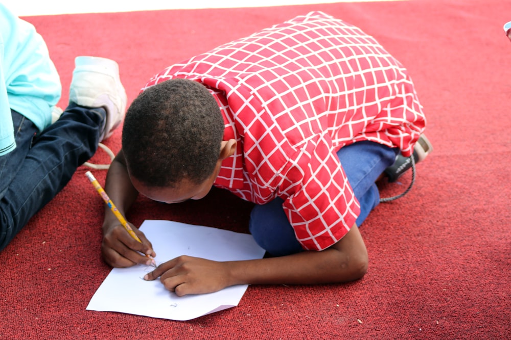 Hombre con camisa abotonada a cuadros rojos y blancos escribiendo en papel blanco