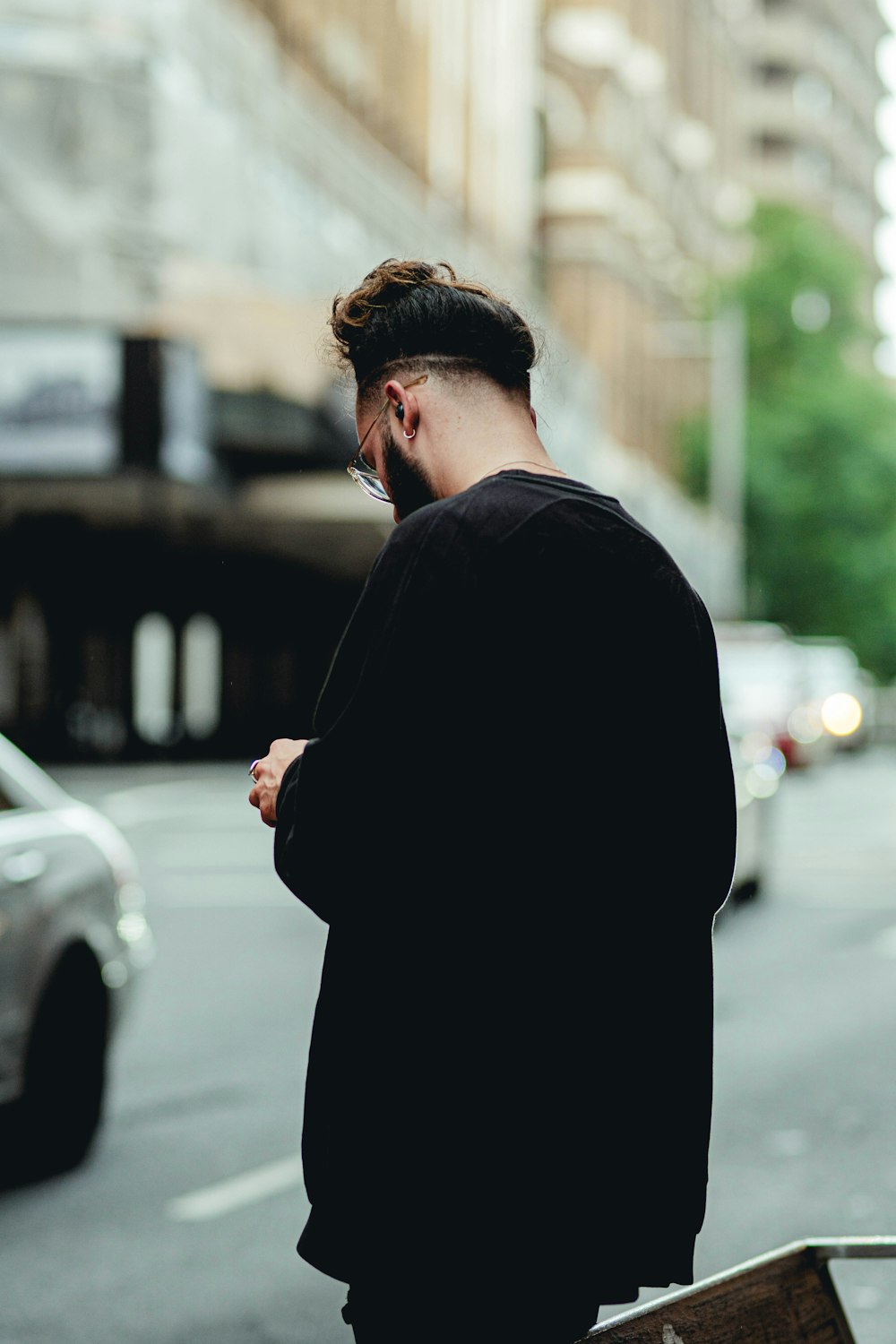 man in black coat standing on sidewalk during daytime