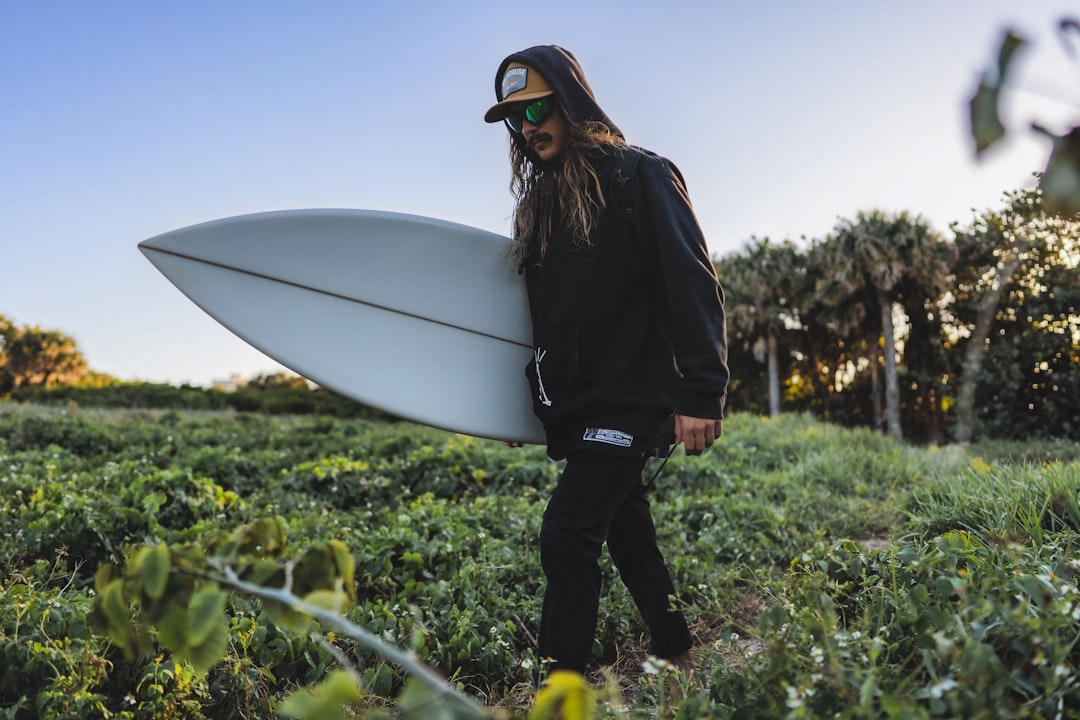 woman in black jacket holding white surfboard