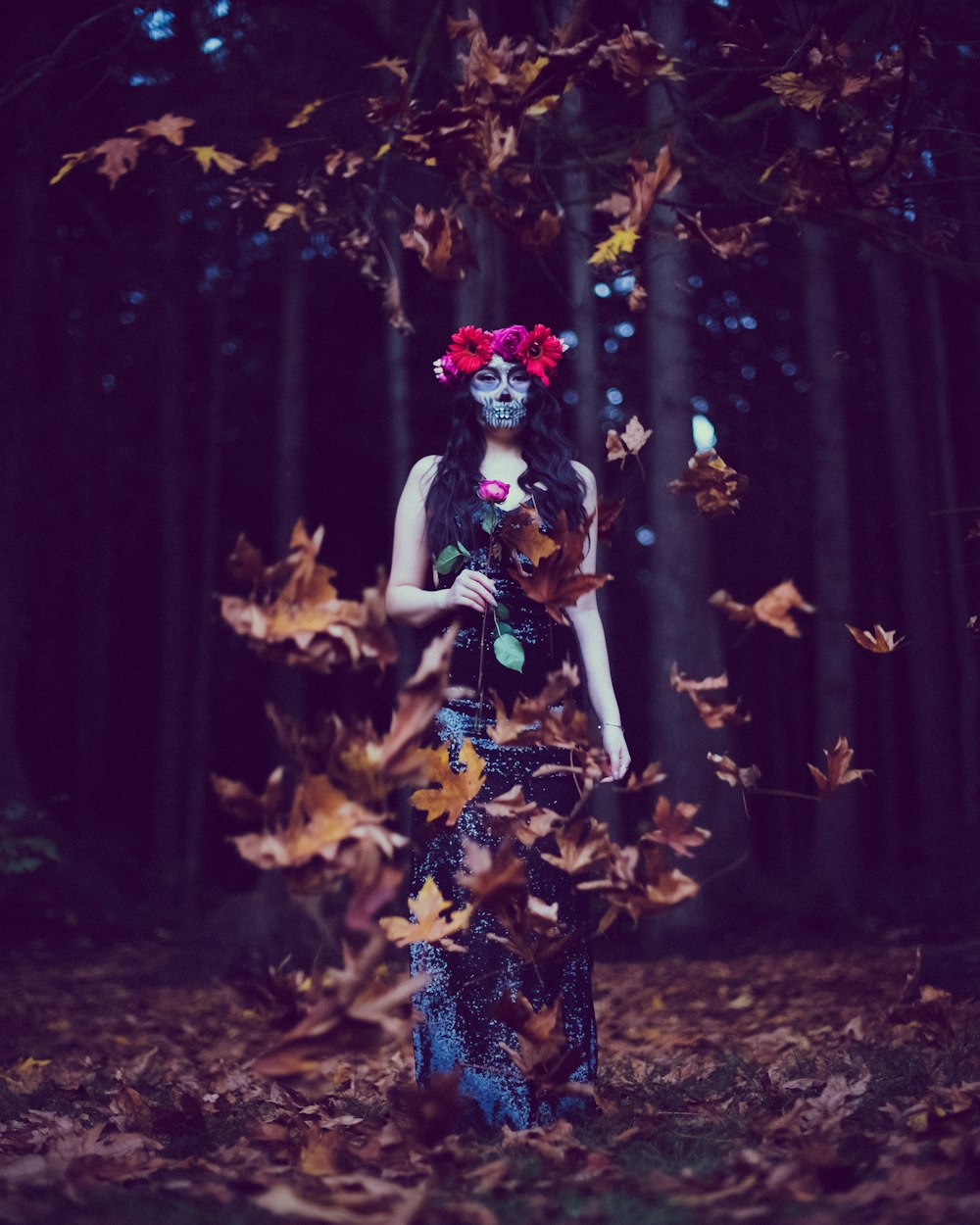 woman in blue and white floral dress standing on brown leaves