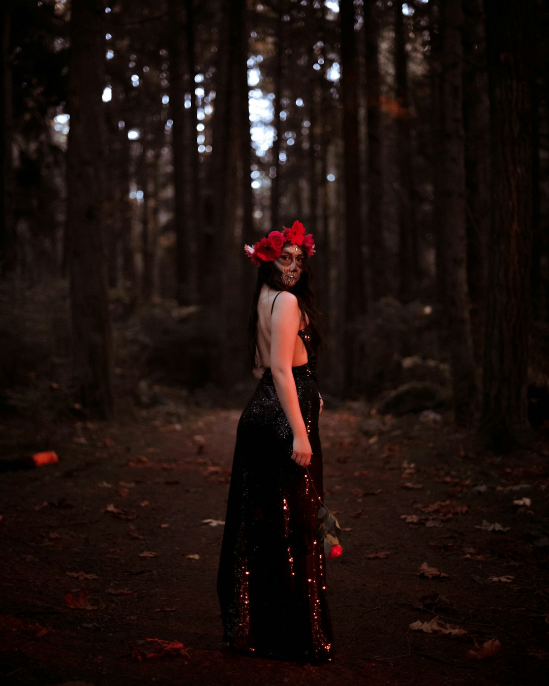 woman in black dress standing in the woods