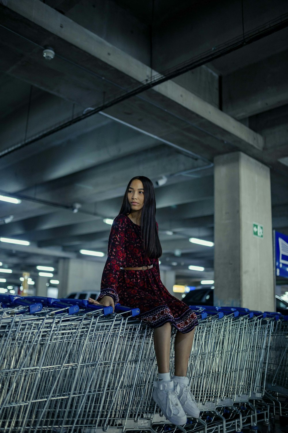 woman in red and black dress sitting on blue shopping cart