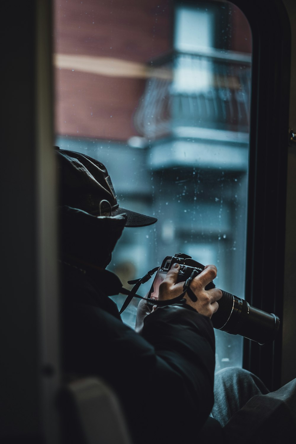 person in black hoodie holding black dslr camera