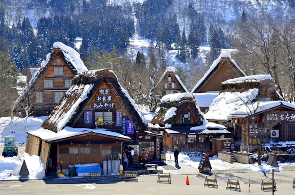 brown wooden house near snow covered mountain during daytime