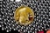 A gold-colored coin with a profile of a warrior wearing a helmet, labeled with '2014' and 'ONE BITCOIN', is surrounded by shiny, metallic beads.