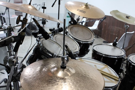 Professional drummer teaching a student in a cozy recording studio filled with drums and microphones.