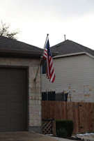 A vibrant American flag painted neatly on a curb beside a suburban driveway.