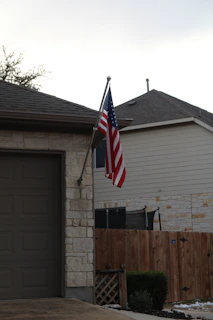 A vibrant American flag painted neatly on a curb beside a suburban driveway.