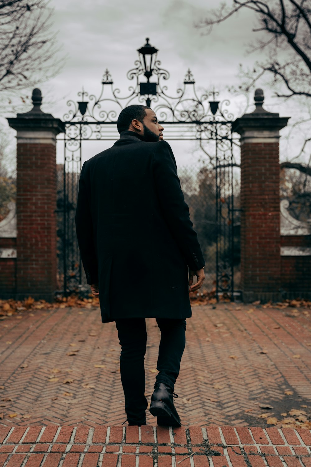 man in black coat standing on brick pavement