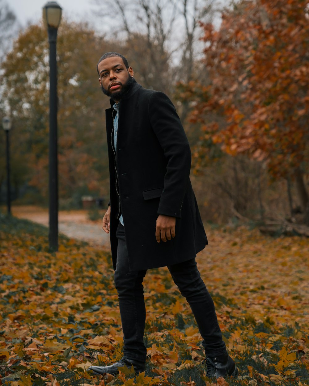 man in black suit standing on dried leaves during daytime