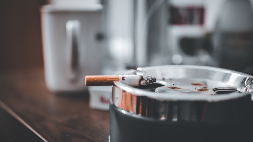 cigarette stick on silver round ashtray