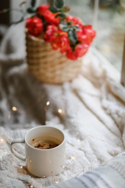 A cozy scene with a warm mug and a soft sweatshirt draped over a rustic wooden fence near a horse pasture.