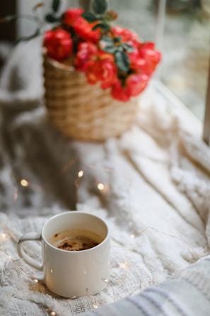 A cozy scene with a patterned mug on a book and knitted blanket in soft light.