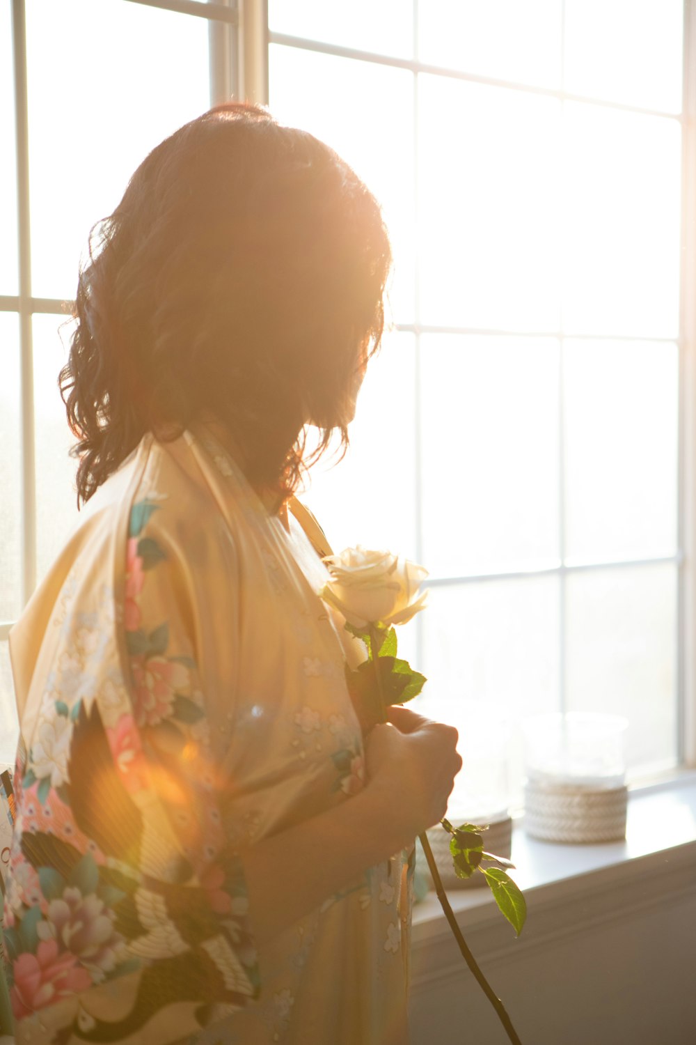 黄色い花を持つ白と黄色の花柄のドレスを着た女性