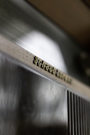 A close-up of a metallic or plastic surface with a brushed texture, featuring an embossed text that reads 'Schaub-Lorenz'. The text appears in gold or brass color on a dark background.