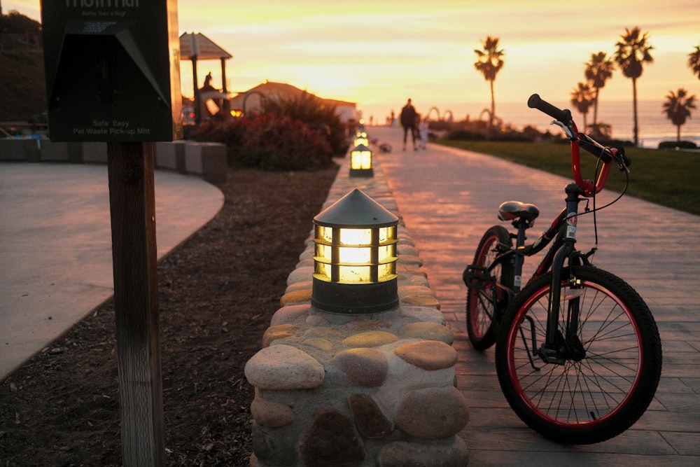 black and red bicycle parked beside black lamp post during sunset