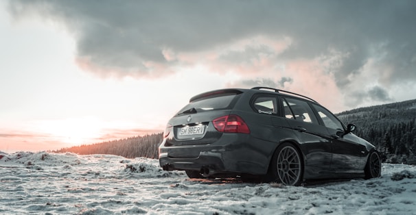 A sleek electric car parked in a snowy Finnish landscape at sunset.