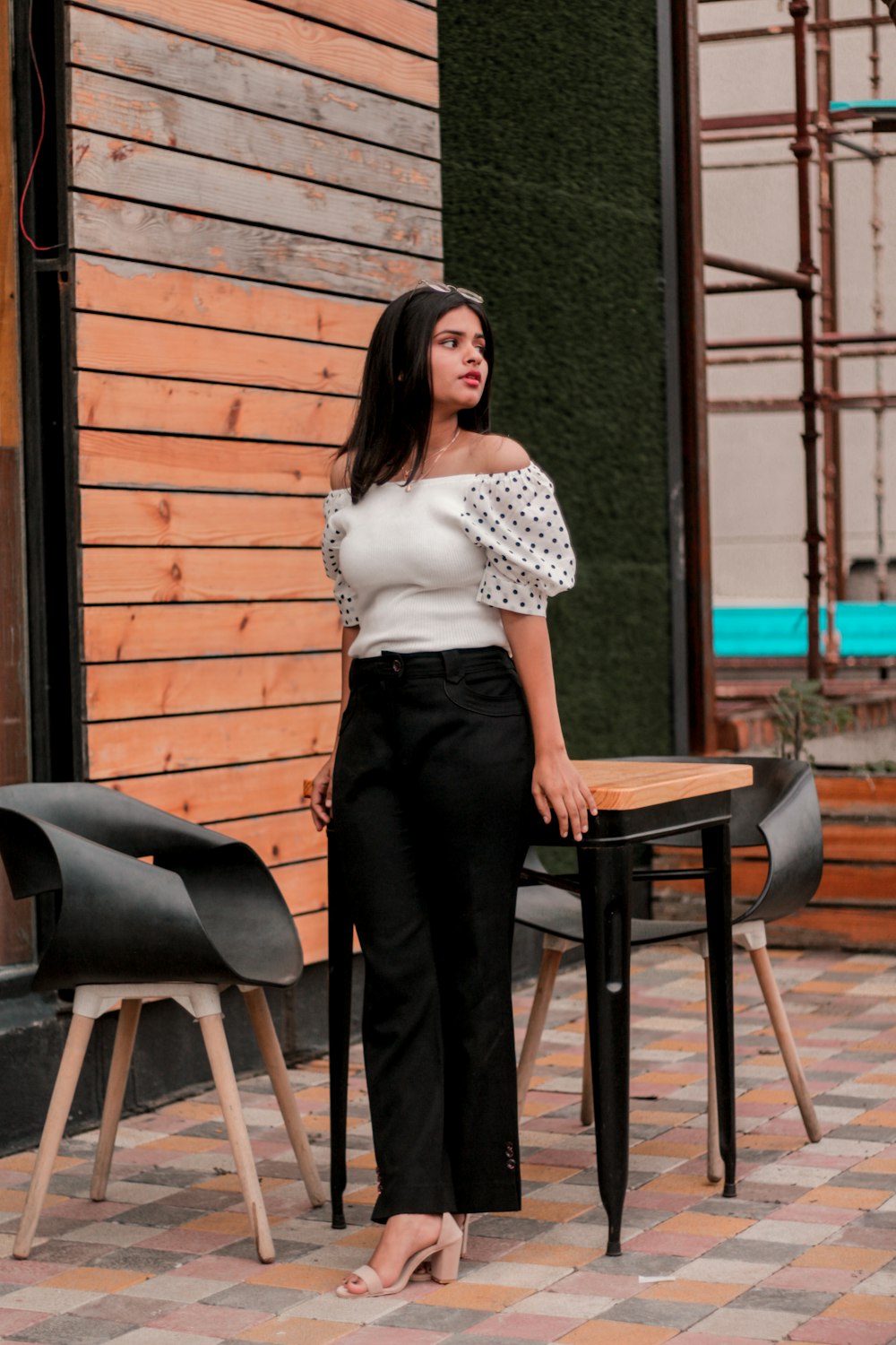 woman in white shirt and black pants standing beside brown wooden table