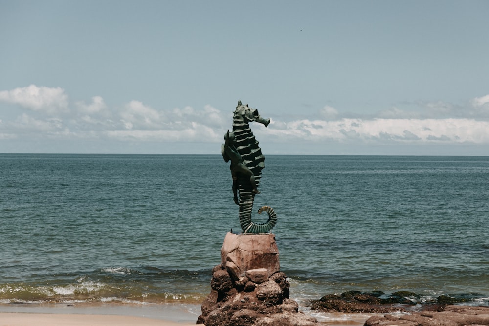 statue of man on rock formation near sea under blue sky during daytime