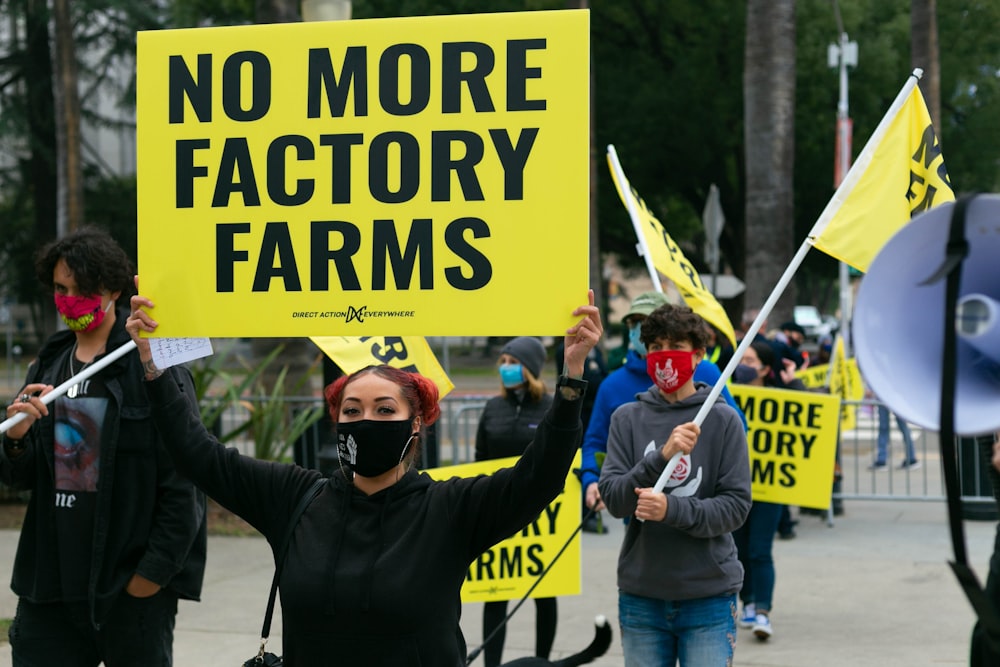 man in black jacket holding yellow and black banner