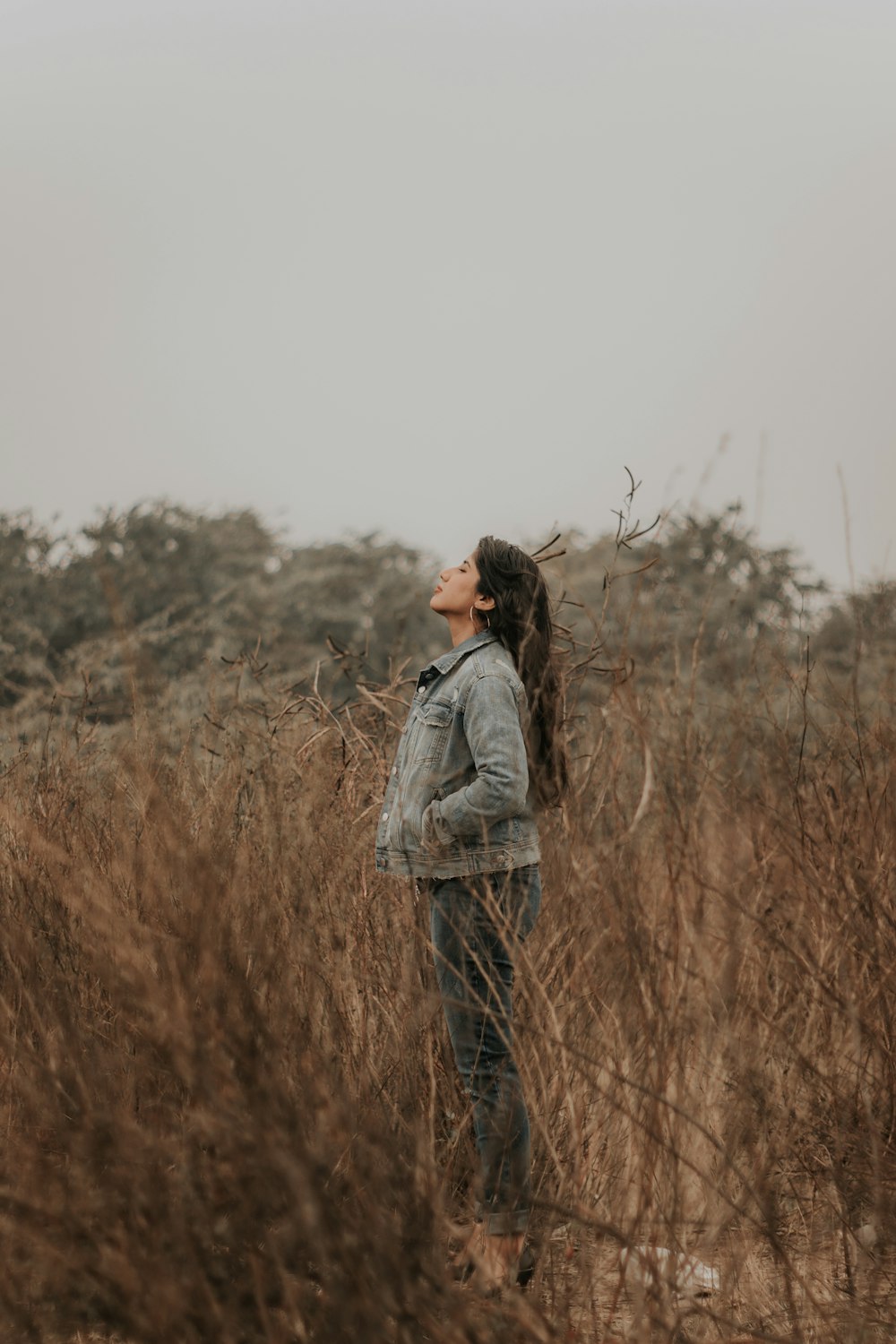 woman in gray jacket standing on brown grass field during daytime