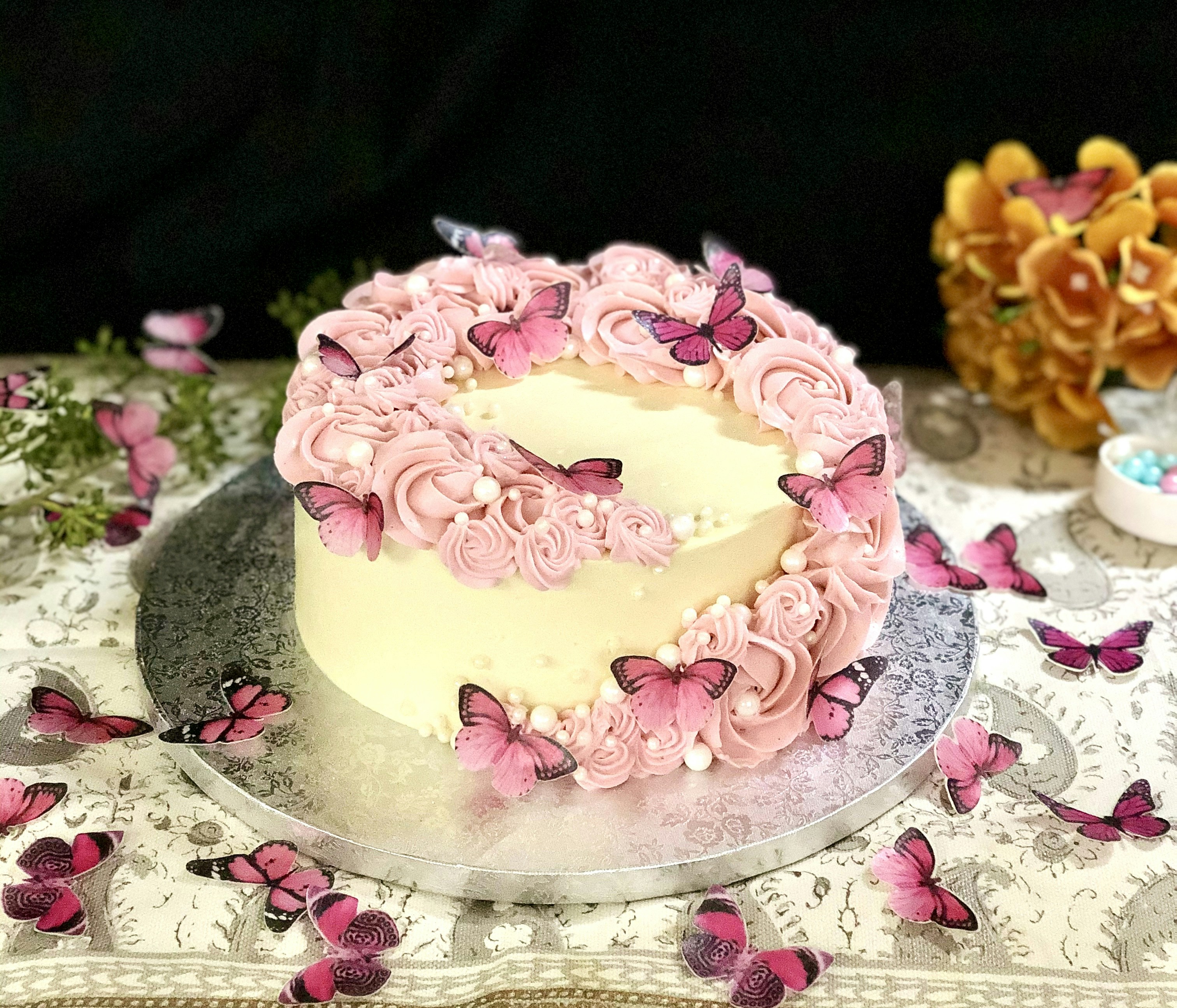Pastel pink birthday cake with buttercream rosettes and fresh flowers