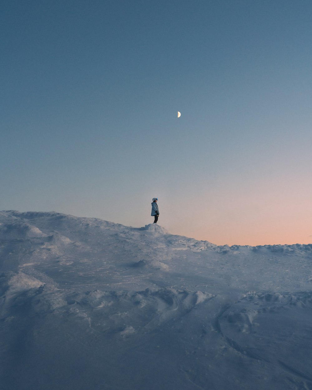 Persona in piedi sulla montagna coperta di neve durante il giorno