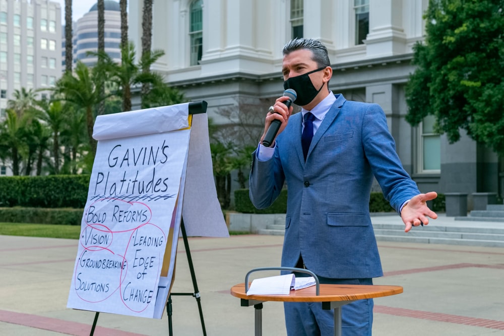 man in blue suit jacket holding white printer paper