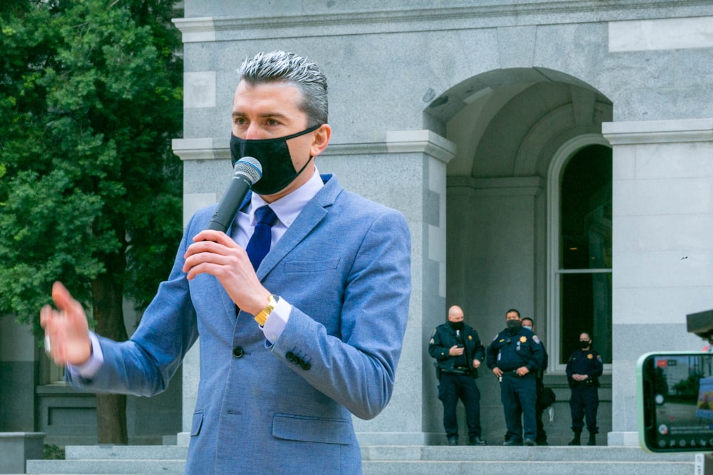 Hombre en traje azul sosteniendo micrófono