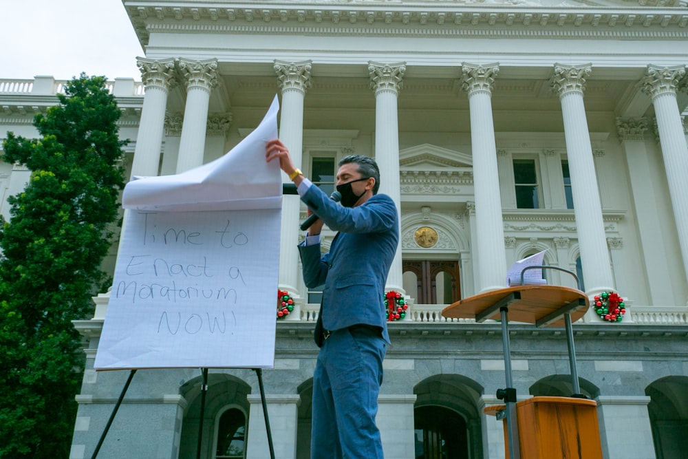 man in blue denim jacket holding white printer paper