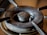 A close-up view of a gas stove burner with visible wear and tear, displaying rust and grime accumulated over time. The metal surface shows discoloration, and the central gas outlet is prominent.