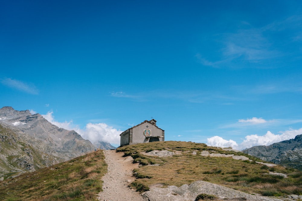 Casa blanca y negra en un campo de hierba verde cerca de la montaña bajo el cielo azul durante el día