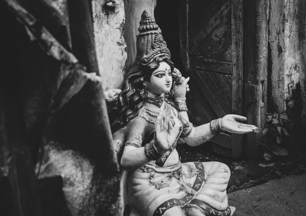 grayscale photo of woman in dress sitting on concrete floor