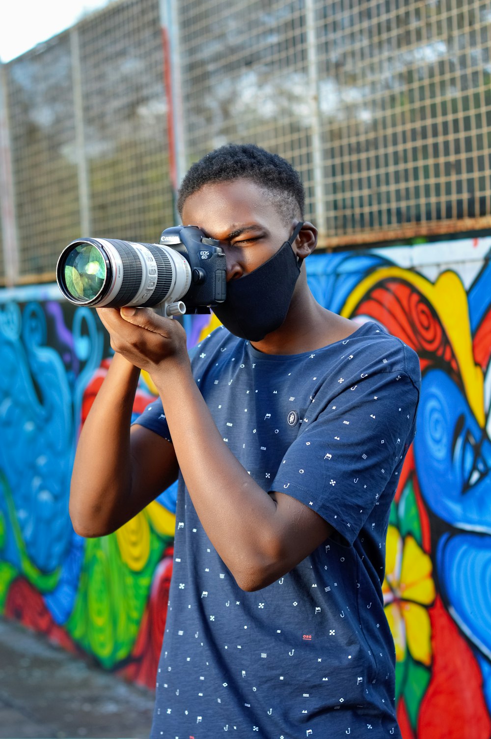 man in blue crew neck t-shirt holding black dslr camera