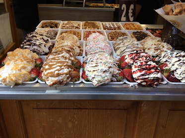 A colorful display of waffles topped with strawberries, chocolate drizzle, and whipped cream.