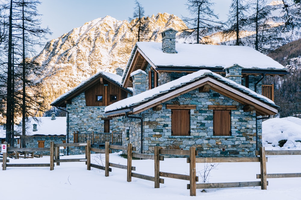 casa de madeira marrom no chão coberto de neve perto de árvores durante o dia