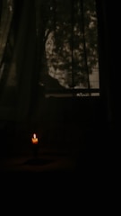 A dimly lit room with scattered pages and a flickering candle casting dancing shadows.