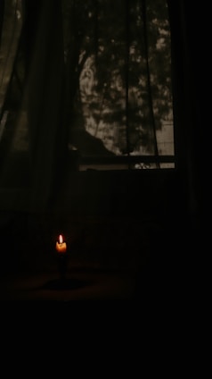 A dimly lit room with scattered pages and a flickering candle casting dancing shadows.