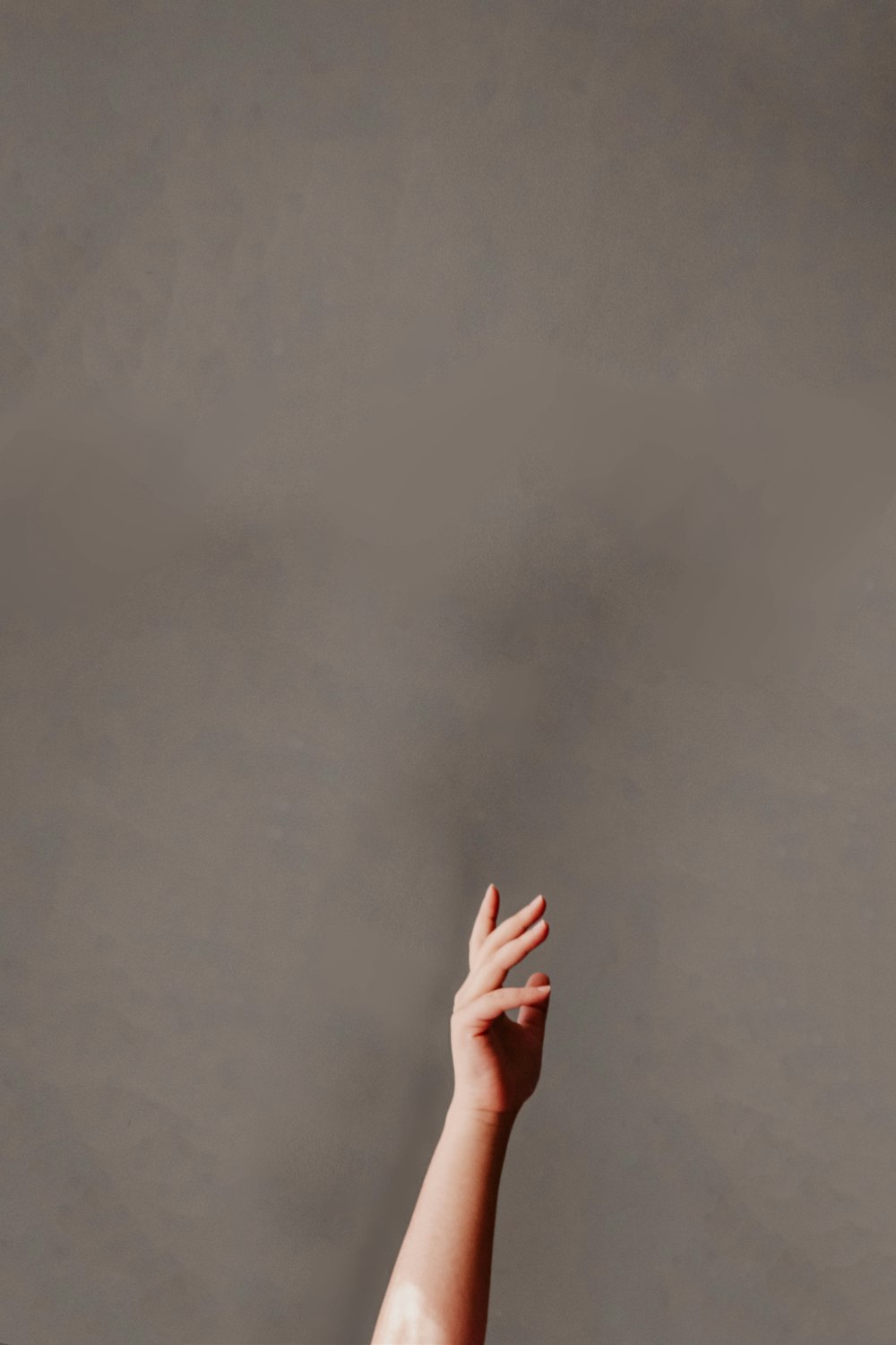 persons hand on gray wall