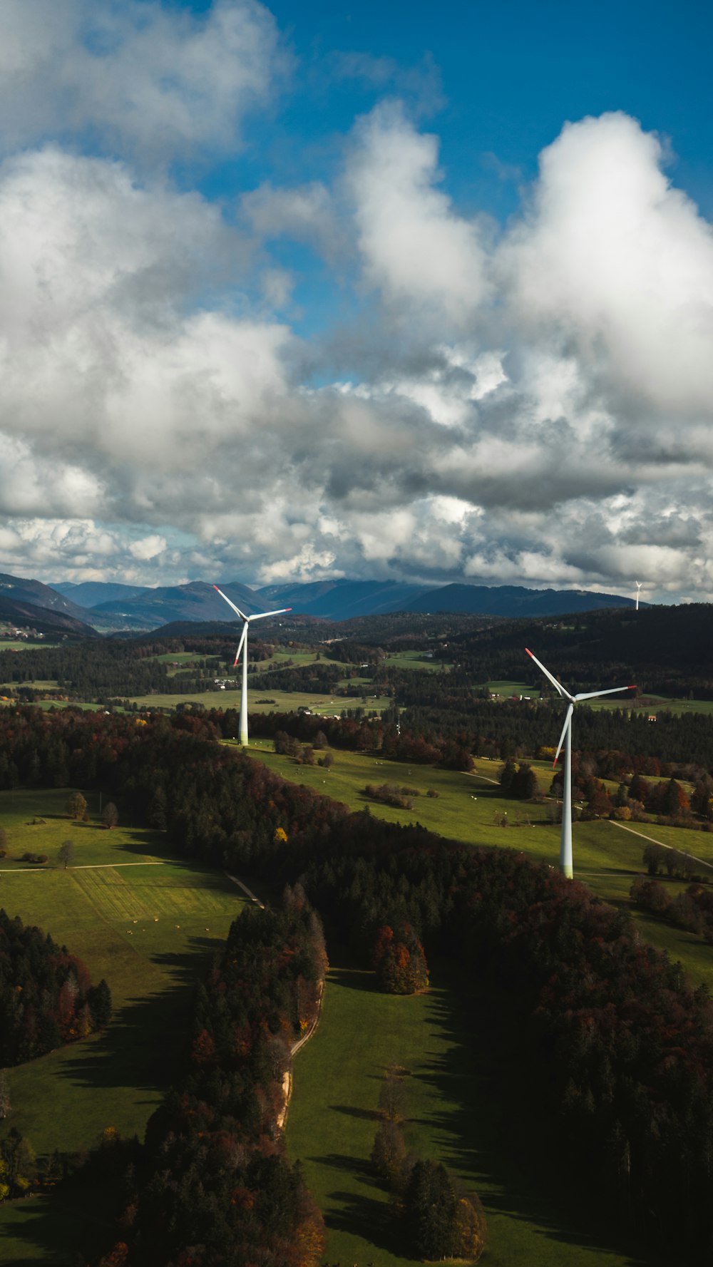 turbina eólica branca no campo de grama verde sob nuvens brancas e céu azul durante o dia