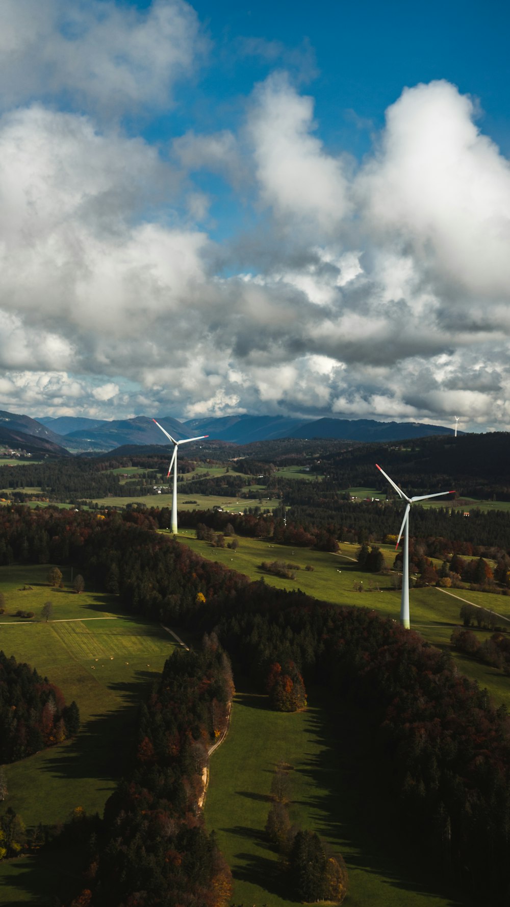 Weiße Windkraftanlage auf grünem Rasenfeld unter weißen Wolken und blauem Himmel tagsüber
